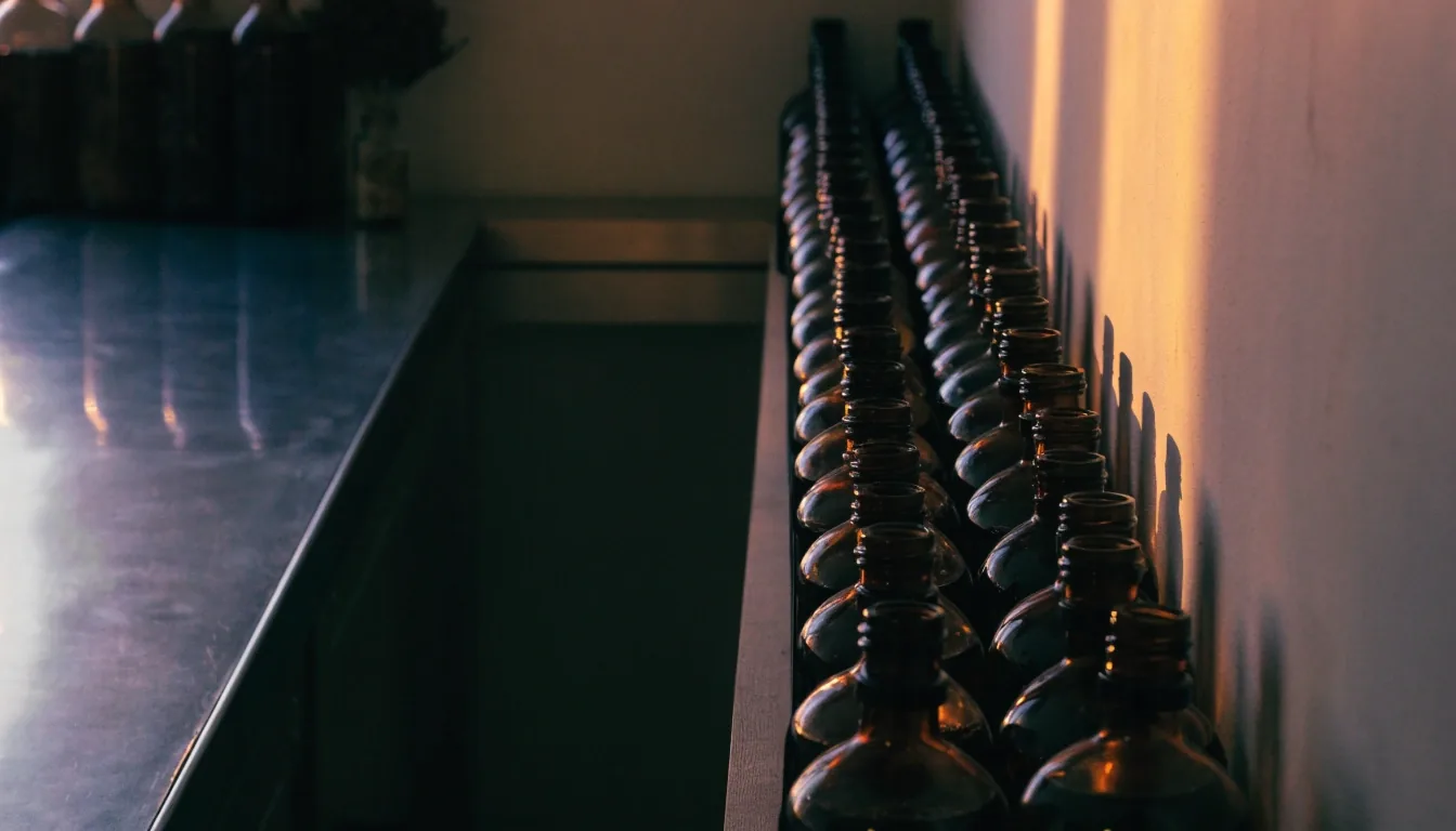 Compounding room shelves with unlabeled amber bottles of botanical extract under cold sidelight